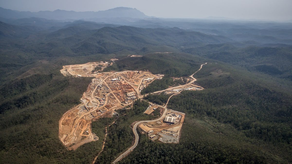 Vista aérea de área industrial em meio a floresta.