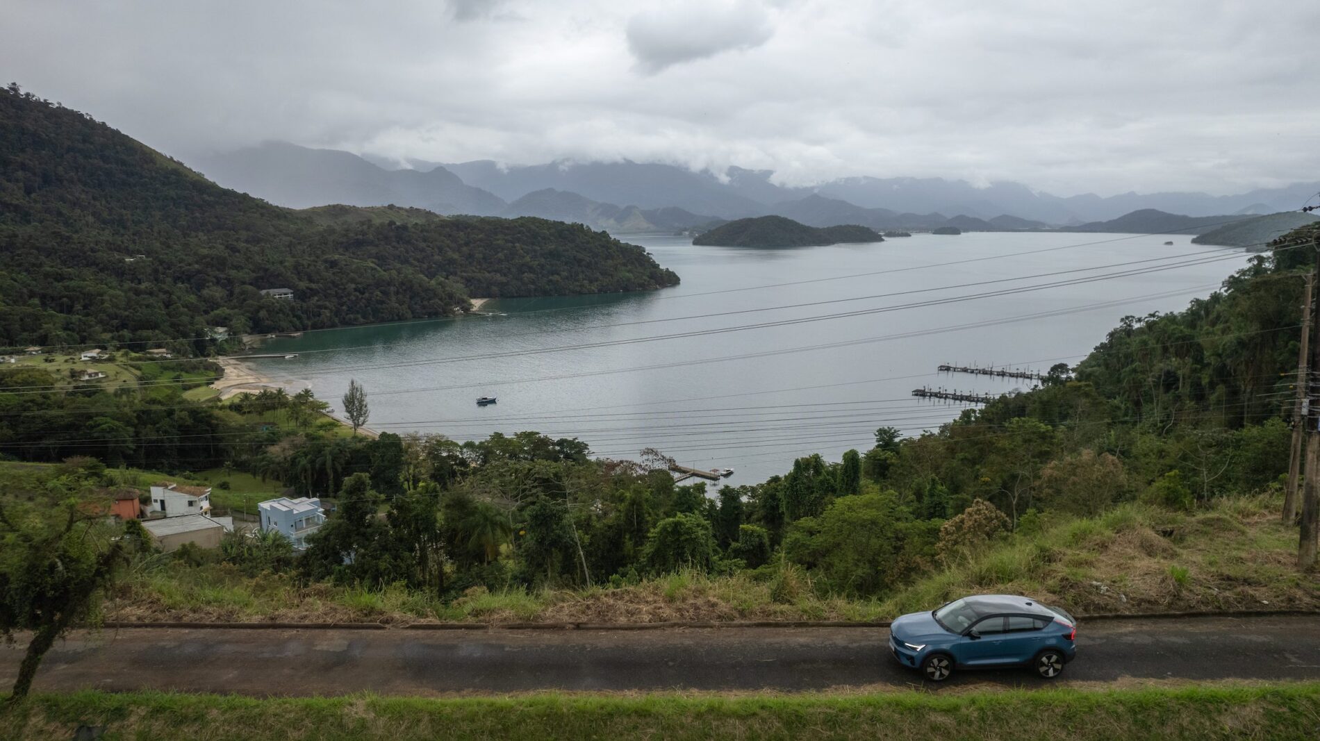 Um carro dirige por uma estrada perto de um lago e montanhas.