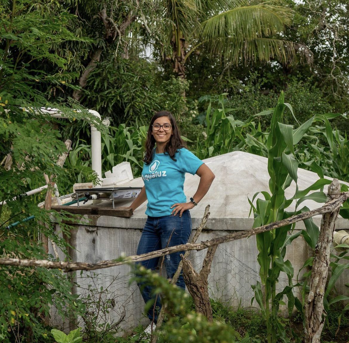 Uma mulher de camisa azul ao lado de um tanque de água.