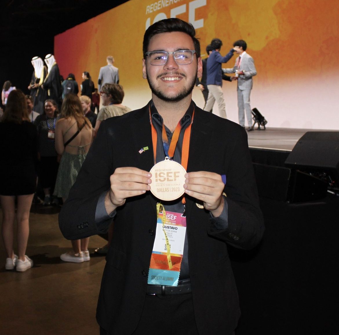 Um homem segurando uma medalha em um evento.