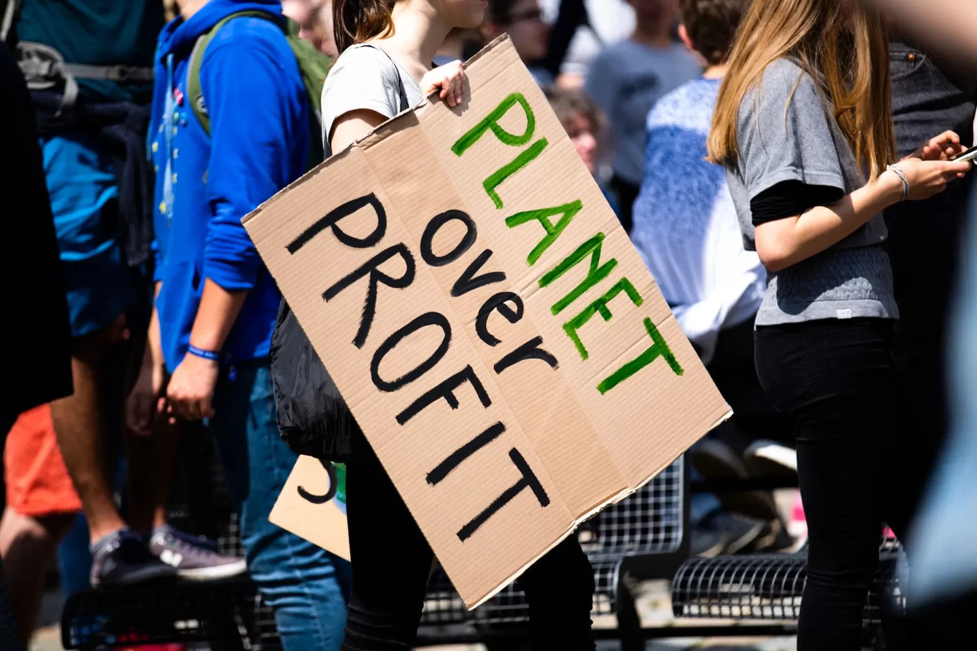 Mulher segurando cartaz com a frase planeta antes do lucro