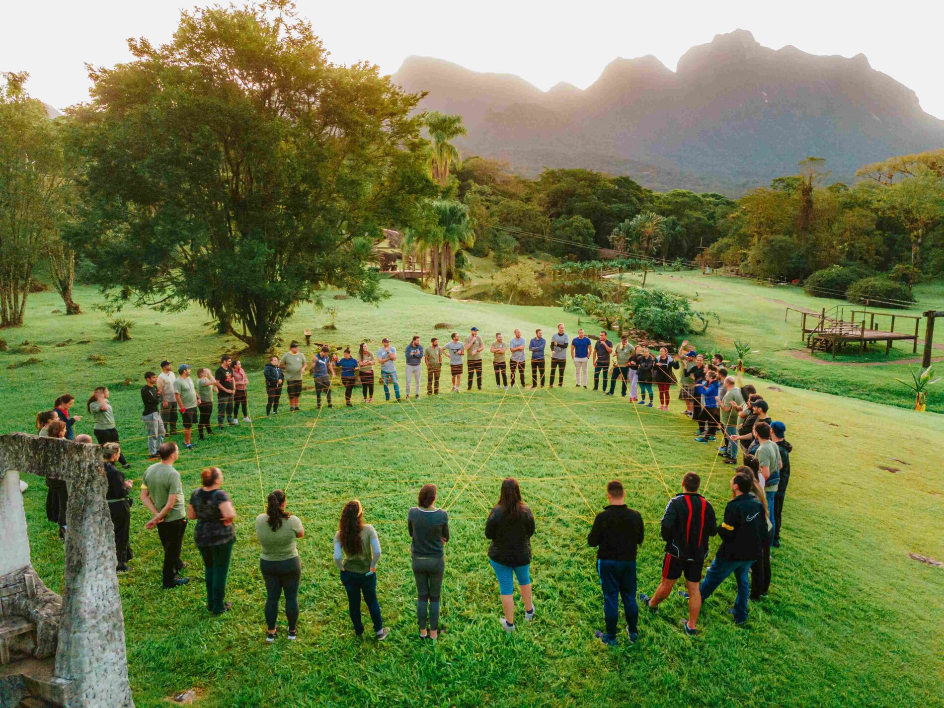 Imagem de um grupo de pessoas em círculo em um campo gramado.