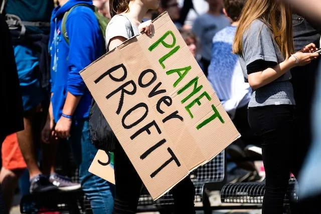 Mulher segurando cartaz que defende o planeta antes do lucro