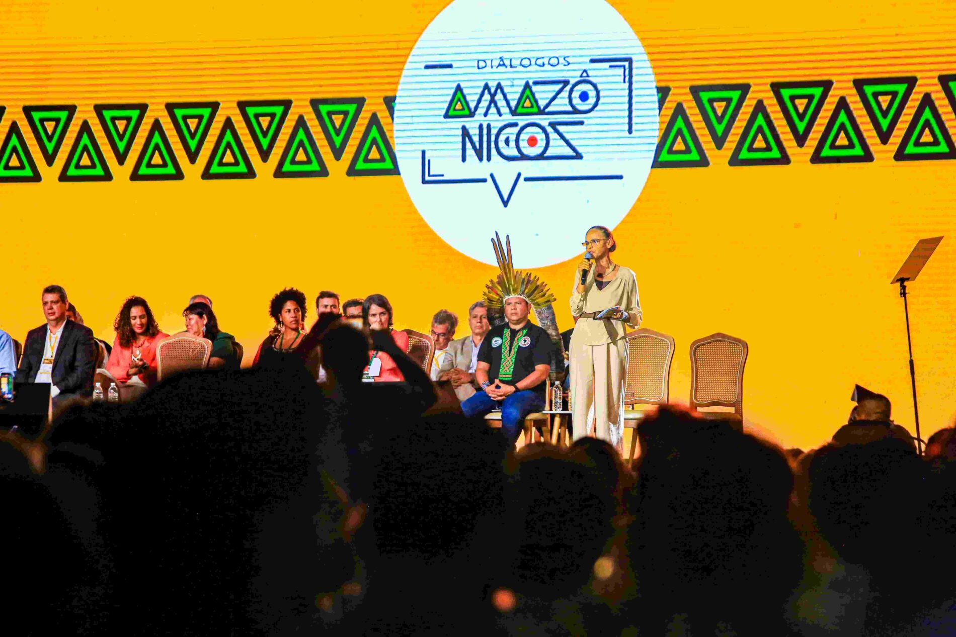 Imagem de uma mulher falando no palco durante um evento.