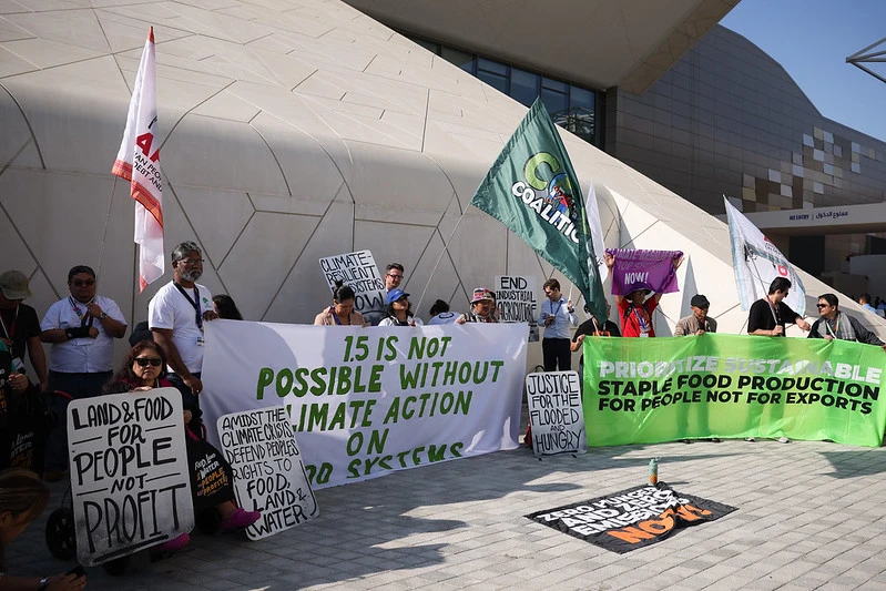 Pessoas seguram cartazes com dizeres sobre ação climática e justiça climática na COP28