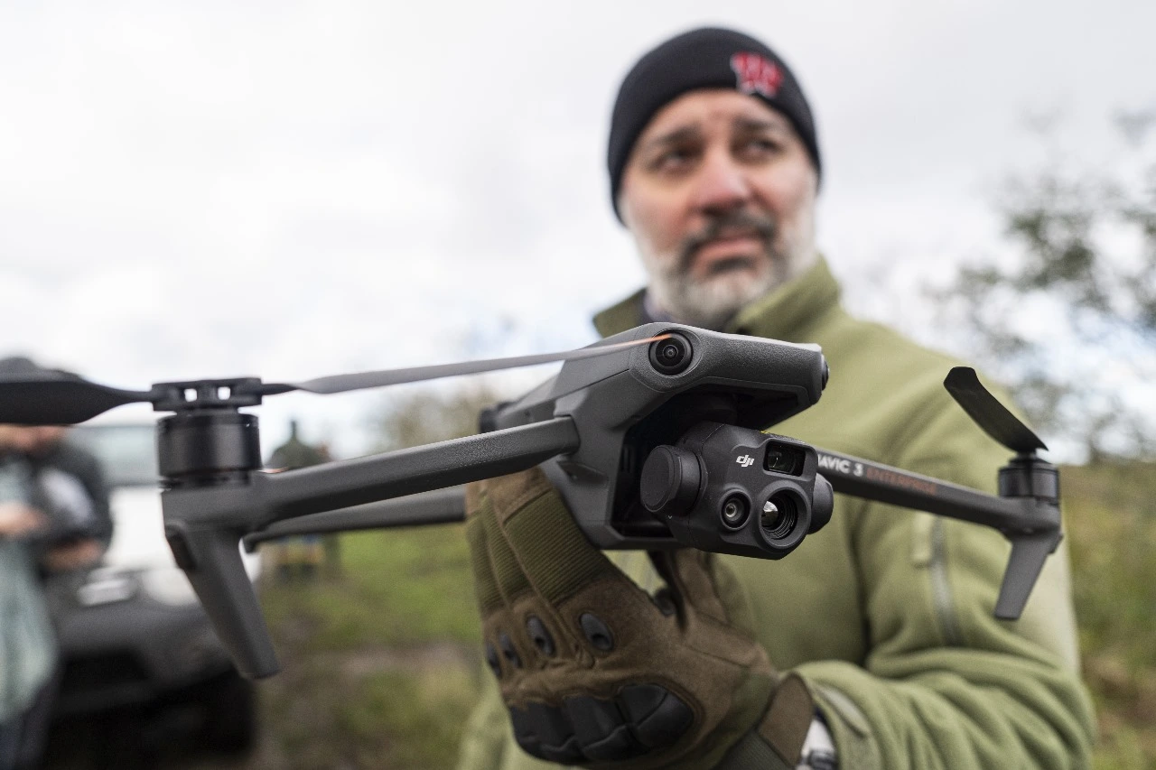 Homem segurando drone nas mãos.