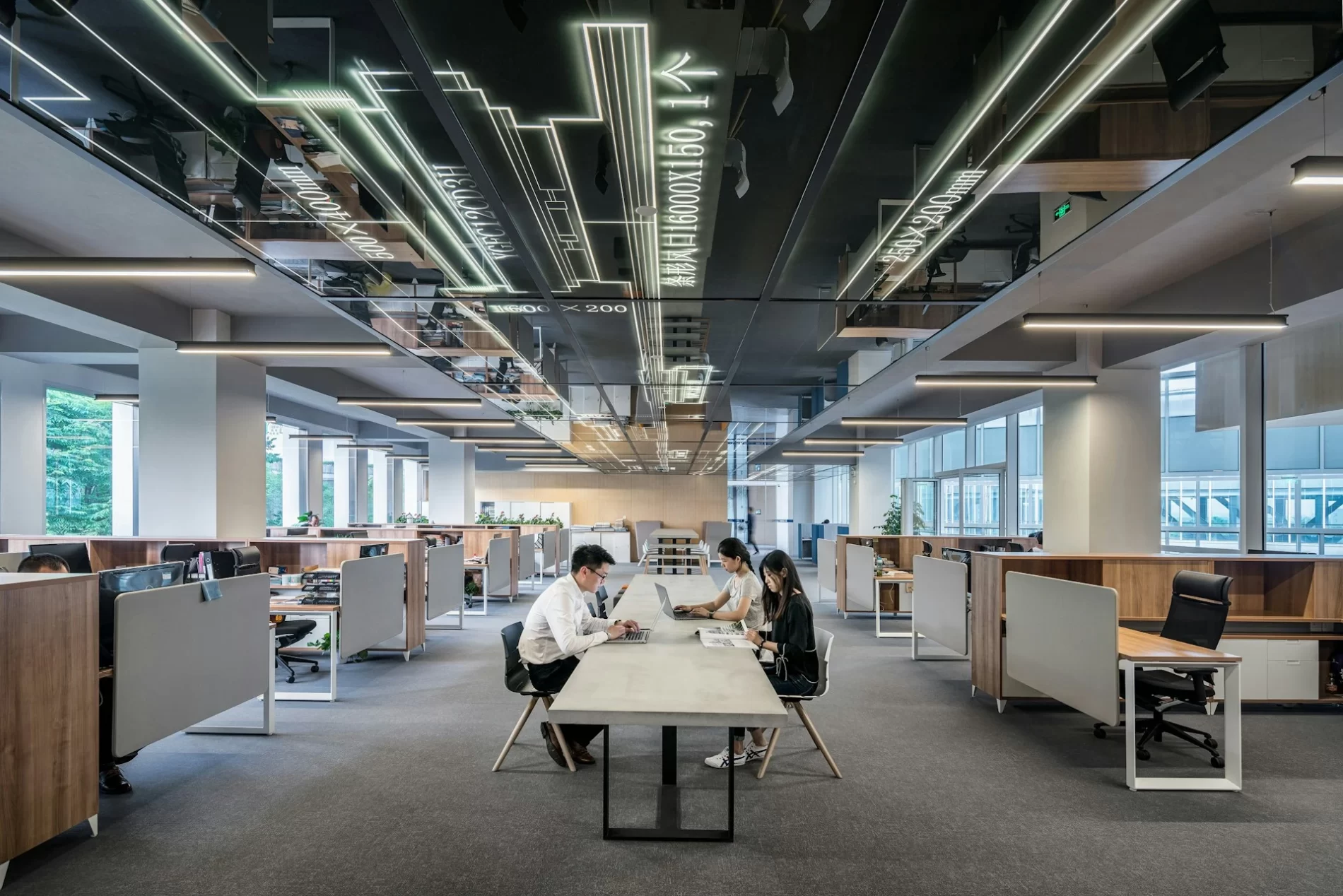 Ambiente de escritório com uma mesa de trabalho ao centro e pessoas trabalhando